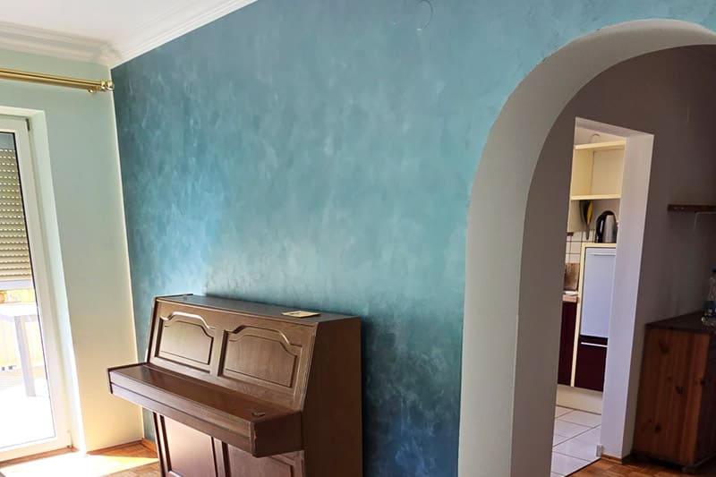 Neuer Anstrich in Blau-Türkis-Tönen einer Wand in einem Wohnzimmer